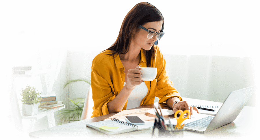 Woman in yellow using laptop while drinking coffee