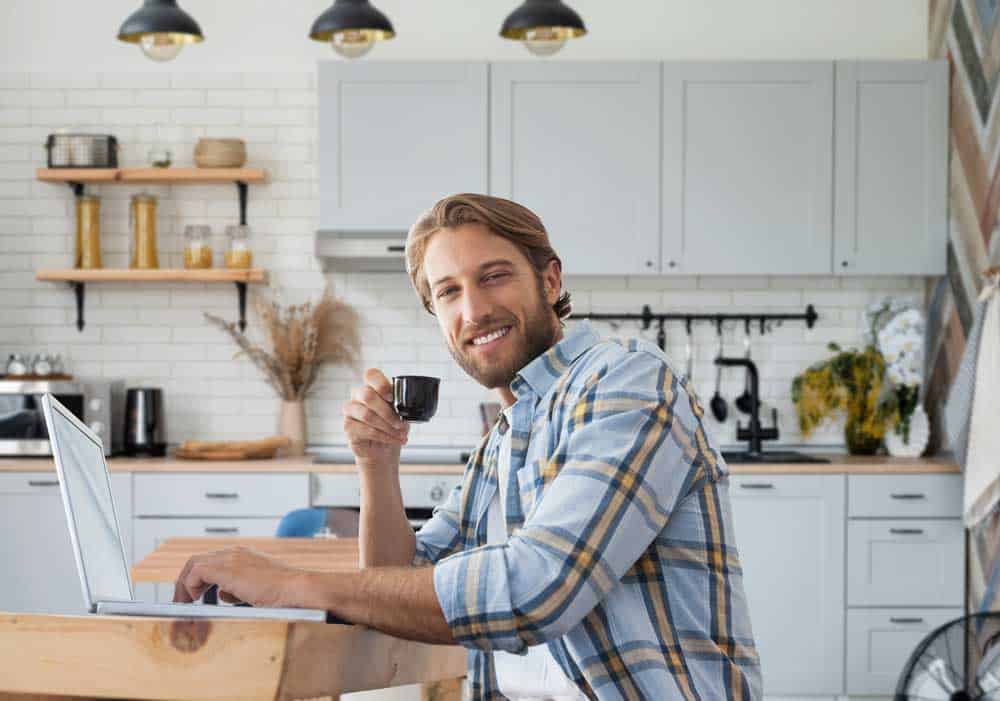 Man drinking coffee while working on laptop
