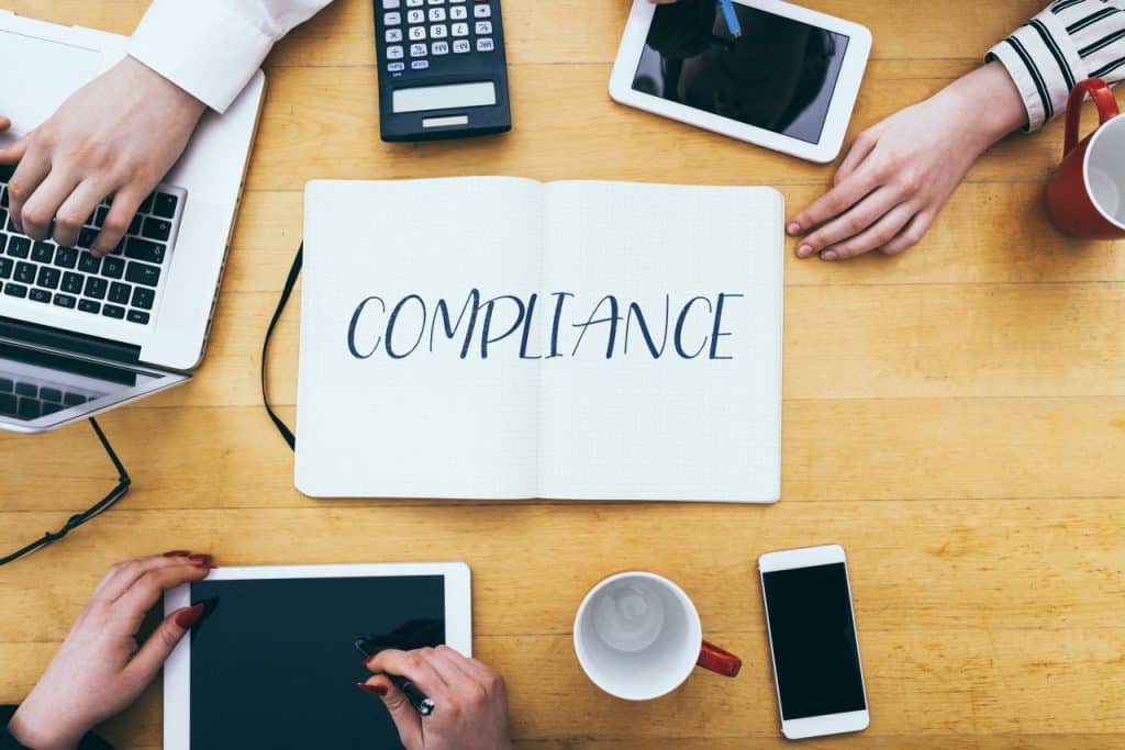compliance written on paper on table with electronic devices